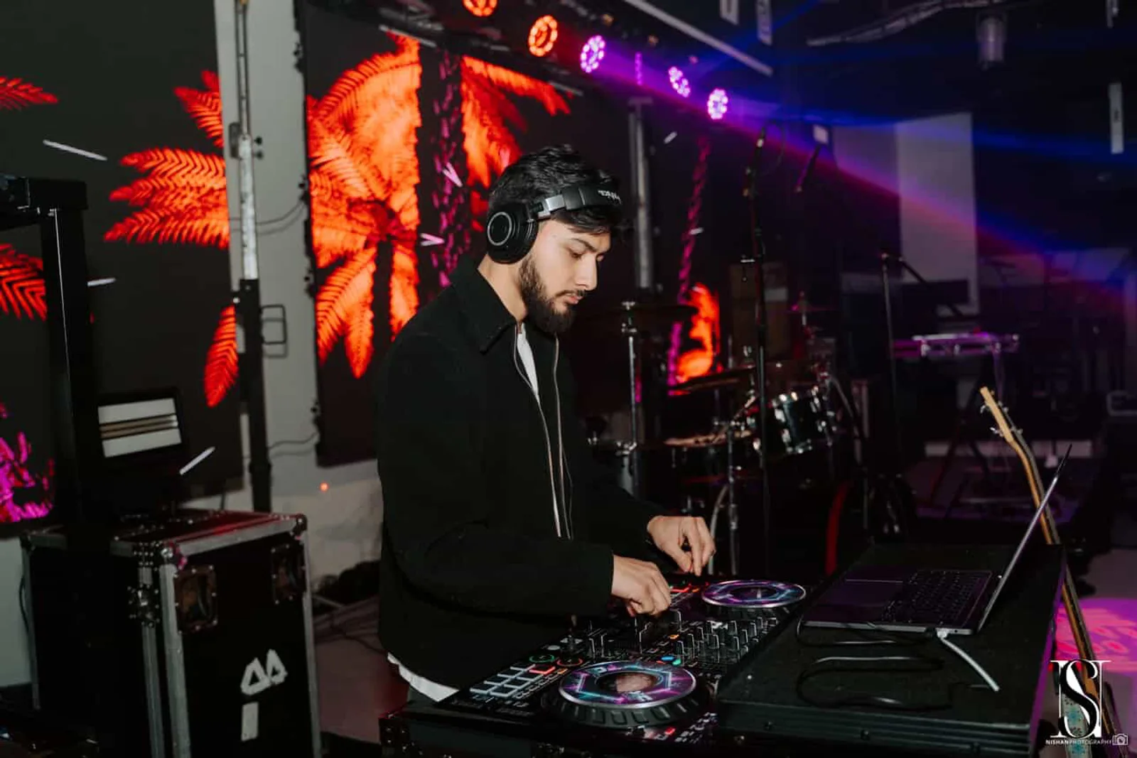 DJ Sarif on the decks under neon palm-tree LED walls