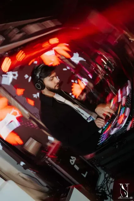 DJ Sarif mixing under red confetti light